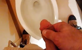 Stroking his cock while peeing in toilet