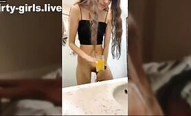 Russian woman drinks dark liquid from glass in bathroom